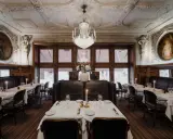 Elegant dukade bord med levande ljus i en av Stockholms gamla restauranger. Kristallkrona och konst pryder taket.