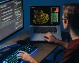 Młody big data engineer analizuje dane na ekranach, tworząc wizualizacje i pisząc kod.
