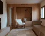 Salones pequeños con mueble de madera integrado, sofá, sillón blanco y alfombra a rayas.