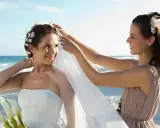 Panna młoda na plaży, jej druhna poprawia welon. Ile razy można być świadkiem na ślubie?