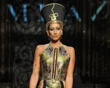 A model wears a striking Nefertiti-inspired headdress and ornate gold and black gown, showcasing the bold vision of Egyptian fashion designers.