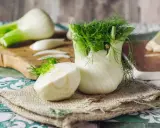 Fenouil frais, prêt à révéler ses bienfaits. Une moitié coupée montre sa texture croquante, tandis que le bulbe entier déploie ses feuilles aériennes.