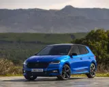 Un Skoda Fabia 130 azul brillante, con techo negro, aparcado en un paisaje montañoso.