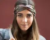 Frau mit braunen Haaren und einem gemusterten Haarband, das ihre Frisur mit Haarband unterstreicht.