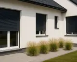 Nowoczesny dom z białym tynkiem, okna z czarnymi roletami zewnętrznymi, które dodają elegancji.