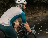 Ciclista con casco e occhiali pedala su strada bagnata, godendosi l'aria fresca. Un modo perfetto per alternare bici e camminata.
