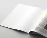 Pagina di rivista aperta, con testo "Essential vacation items" su carta satinata.