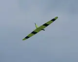 Ein gelb-schwarzes Flying Wing Segelflugzeug gleitet elegant durch den wolkenverhangenen Himmel.