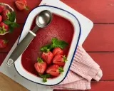 Orzeźwiający lody truskawkowe sorbet w naczyniu, ozdobione świeżymi truskawkami i miętą. Idealny na upalne dni.