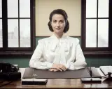 Elegancka sekretarka w białej bluzce siedzi przy biurku, gotowa na kolejne zadanie.