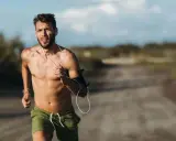 Ein Mann läuft bei Hitze, sein Puls rast. Er trägt Kopfhörer und eine Armbinde für sein Handy.