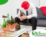 Smutny mężczyzna w czapce Mikołaja siedzi z butelką piwa, otoczony pustymi butelkami. Szukasz co zamiast alkoholu?