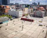Rynek w Katowicach z czerwonym tramwajem i ludźmi spacerującymi po placu. Idealne miejsce na odkrywanie katowickich atrakcji dla młodzieży.