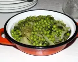 Un plat de petits pois et légumes verts, assaisonnés d'herbes, dans une cocotte orange. Une recette simple et savoureuse.