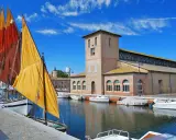 Vele colorate di barche tradizionali ormeggiate nel porto canale di Cervia mare, con l'antico edificio delle saline sullo sfondo.
