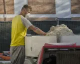 Budowlaniec w masce przygotowuje beton konopny.