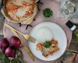 Ein Rotbarschfilet mit Senfsauce, serviert mit Reis und garniert mit Kresse. Dazu passen rote Zwiebeln und ein Glas Weißwein.
