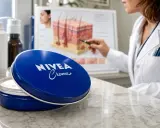 Boîte de crème Nivea bleue ouverte, avec une experte expliquant les bienfaits de la crème sur la peau.