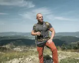 Mężczyzna w letnim stroju górskim: koszulka, spodnie trekkingowe i plecak. Idealny przykład, jak się ubrać w góry latem.