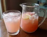 En glas och en karaff med rosa drink, is och citronskivor. Perfekt för en svalkande vodka soda.