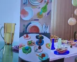 Un joyeux **art de la table française** avec des desserts colorés, des assiettes vives et un pichet jaune.