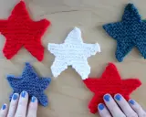Cinco estrellas tejidas de punto estrella, rojas, blancas y azules, dispuestas sobre una superficie de madera.