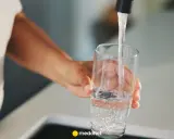 Ręka nalewa wodę do szklanki. Zastanawiasz się, kiedy skończy się woda pitna? Dbajmy o zasoby.