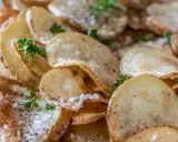 Krispiga, gyllene skivor av friterad potatis, strödda med salt och peppar, toppade med färsk persilja.