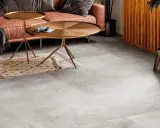 Un elegante soggiorno con divano in pelle color caramello, tavolini dorati e un tappeto etnico su un **pavimento grigio** che crea **abbinamenti** moderni e sofisticati.