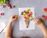 Dziecko tworzy bukiet z kolorowego makaronu farfalle na laurce. Świetne pomysły na laurki!