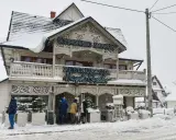 Drewniana chata z napisem "Schronisko Smaków" i neonem "Restauracja" w Bukowinie Tatrzańskiej, otoczona śniegiem.