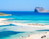 Rajska plaża z turkusową wodą i skalistą wysepką w oddali. Czy to Rodos czy Kreta? Trudno odróżnić ten cud natury.