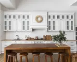 Cuisine lumineuse avec des armoires blanches et un îlot en bois massif. On dirait qu'on a réussi à faire une cuisine avec des vieux meubles, le tout dans un style rustique chic.