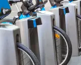 Des vélos bleus et gris sont rangés, prêts à recharger sur une borne auto.