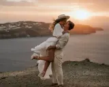 Pareja besándose al atardecer, ella en brazos de él, con un aire de bodas ibicencas.