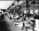 Barn arbetar vid maskiner i en verkstad, en scen från den industriella revolutionen.