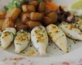 Chipirones a la plancha, tiernos y dorados, acompañados de patatas rústicas y un toque de perejil fresco.