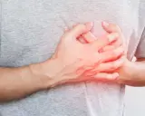 Dłoń na klatce piersiowej, odczuwając niepokojące kołatanie serca w nocy.