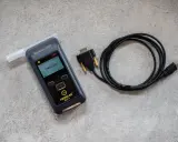 Alkomat z ustnikiem i kablem USB na szarym tle.