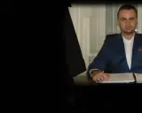 Mężczyzna w garniturze siedzi przy biurku z dokumentami.