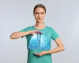 Kobieta w zielonej koszulce prezentuje wirtualne płuca, symbolizujące fizjoterapię oddechową.
