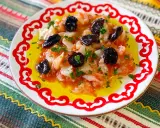 Esqueixada de bacalao con aceitunas negras y perejil, servida en un plato blanco con borde rojo sobre un mantel colorido.