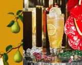 En läcker drink med Xante, garnerad med lime och en flamingotopp. Päron på en gul bakgrund till vänster.