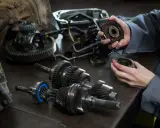 Mechanik analizuje części skrzyni biegów, szukając przyczyny, dla której sprzęgło skrzypi przy puszczaniu.