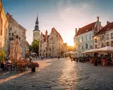 Solnedgång över kullerstensbelagd torg i Tallinn, med uteserveringar och historiska byggnader. Perfekt för **europa tips**.