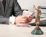 Un homme en costume compte des billets d'euros, une balance de la justice à proximité. La question se pose : le donateur peut-il vendre un bien donné en donation ?