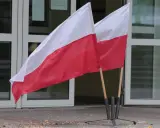 Dwa polskie flagi przed budynkiem. Dowiedz się, jak głosować za granicą, by Twój głos miał znaczenie.