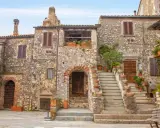 Un angolo di **Toscana, cosa vedere: borghi** antichi con case in pietra, scale fiorite e un'atmosfera senza tempo.
