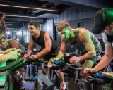 Intensywny trening spinningowy w grupie. Ludzie z determinacją pedałują na rowerach stacjonarnych, pocą się i walczą o każdy kilometr.