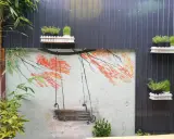 Un columpio pintado en un muro, ideal para inspirar al pintar patios pequeños. Las ramas anaranjadas y el bambú añaden color.